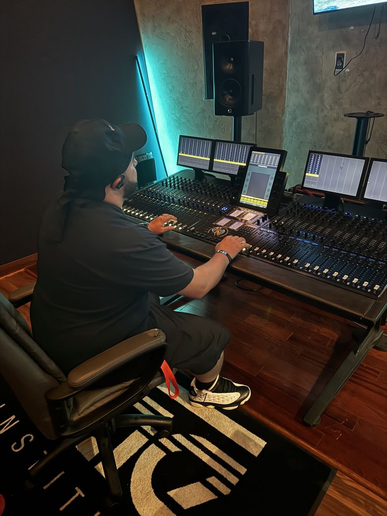 Gemini working the faders on a large mixing console